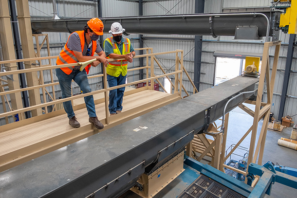 Workers inspecting machinery in almond processing plant